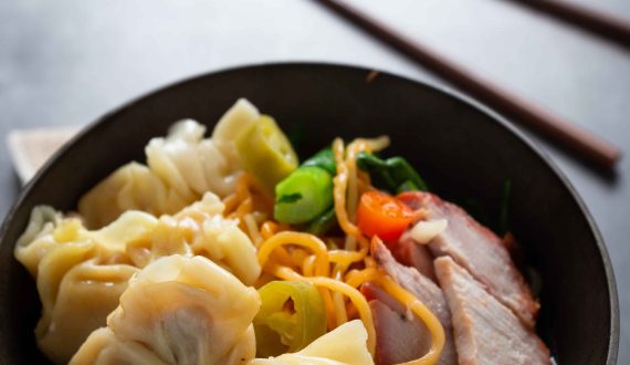 Egg noodle with red roasted pork and wonton on table.